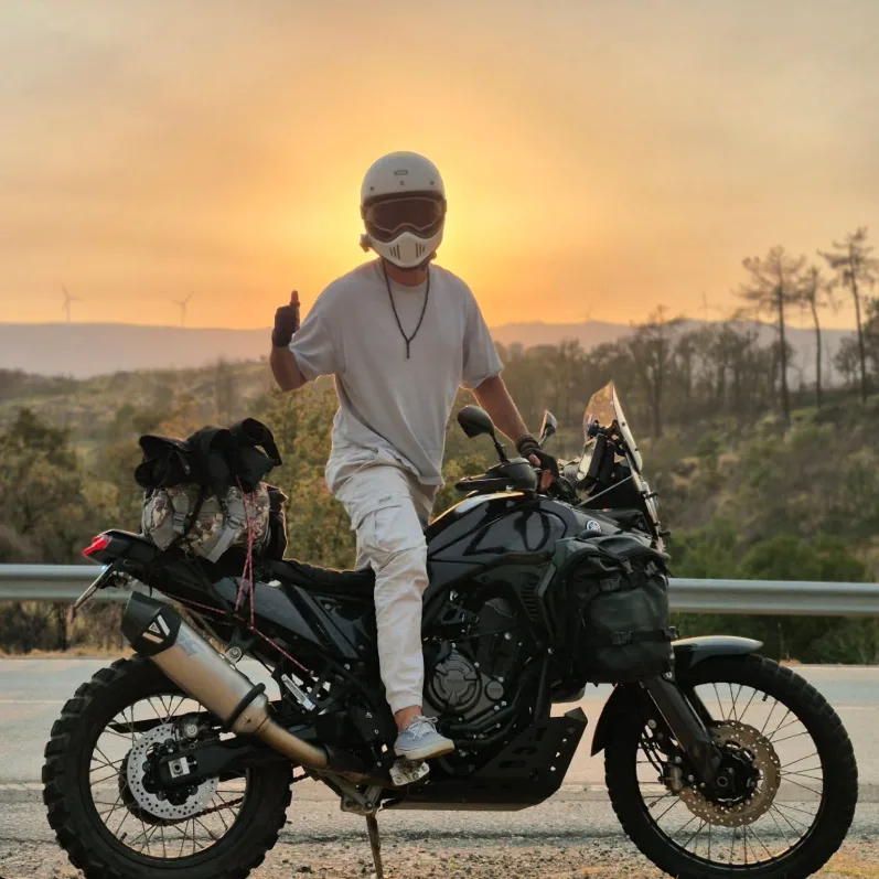 Pedro Carimo de capacete ao lado da mota ao pôr do sol